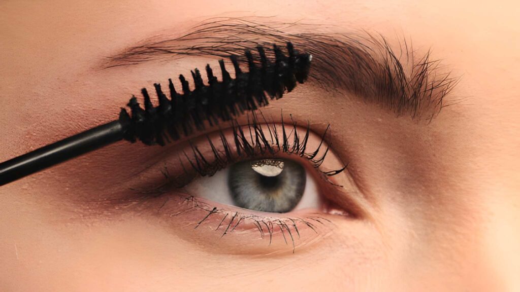 Beauty makeup photography featuring mascara application on eyelashes and eyebrow in an extreme close-up shot.