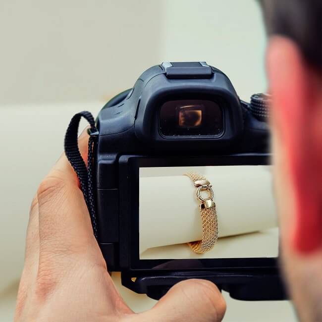 a product photographer shoots jewelry product photos with a white beige color background.