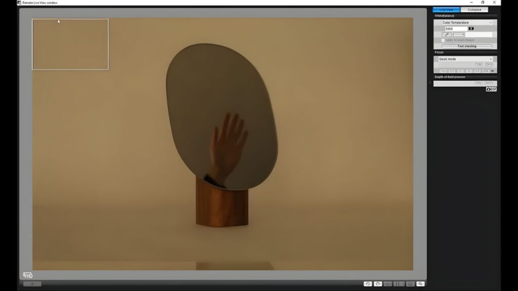 A hand reaches out from behind an oval mirror on a wooden stand against a beige background. The image is displayed on a computer screen with editing tools visible.