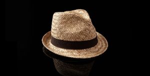 A brown hat on a black surface focusing reflection shadow service.
