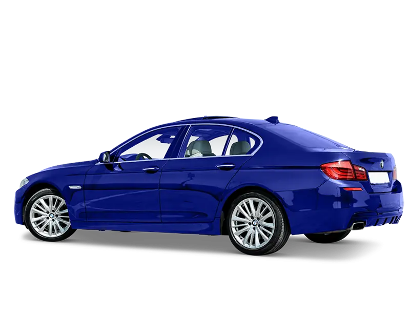 A blue sedan with sleek design elements is shown from the rear side angle. The vehicle has silver alloy wheels and a streamlined body, with visible rear lights and a dual exhaust system. Captured on a white background, this image showcases precise automotive photo editing.