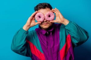 A model is showing two donuts, looking through them in a weird way. 