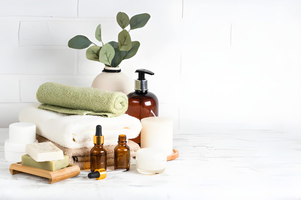 Stack of towels with shampoo bottle, candles, essential oil, and cosmetics