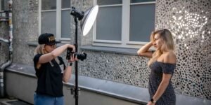 A woman is posing infront of a camera with a beauty dish, and another woman is capturing