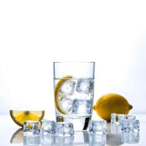 Glass of water with ice cubes and lemon slice, surrounded by ice and lemon on white background.