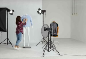 a woman standing next to a mannequin in front of a camera, presenting indoor product photography