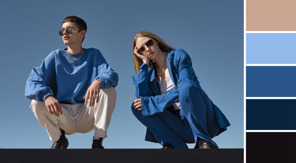Two individuals in stylish blue outfits pose against a clear sky, showcasing a modern aesthetic with a color palette on the side.