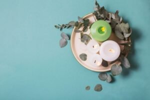 a couple of candles and leaves are on top of a plate and background is paste color. 