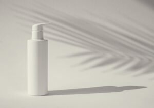 A bottle of lotion sitting next to a palm leaf, where the shadow is mannipulating moods.