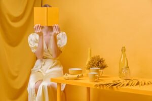 a woman sitting on a table with a book in front of her face, representing lifestyle product photography