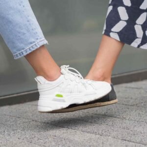 Close-up of a person's feet in white sneakers, one stepping on a ledge, with rolled-up jeans.