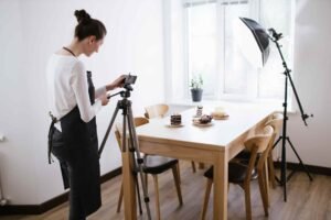 Person photographing desserts on a table with a camera on a tripod and studio lighting.