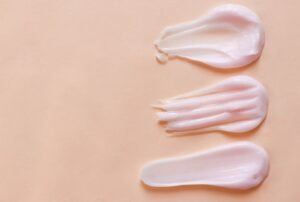 Three distinct types of cream displayed on a beige background, showcasing their varied textures and colors