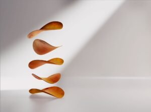 Six maple seeds arranged in mid-air to mimic falling, against a white background with a light beam.