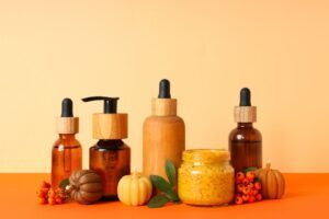 A collection of orange pumpkins and various fall cosmetic products displayed in glass jars, capturing the essence of autumn.