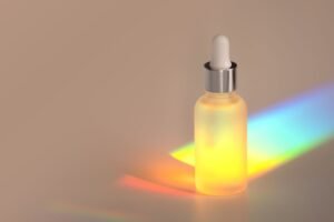 A bottle of cosmetic product emit vibrant rainbow light, creating a colorful display against a neutral background.