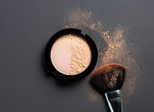 Powder foundation and a brush elegantly displayed on a soft gray background, highlighting beauty essentials for flawless cosmetic product photography. 