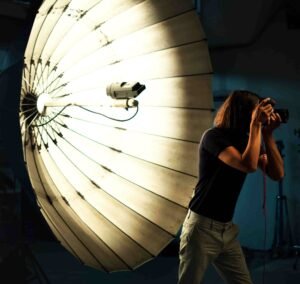 Photographer taking a photo with a large umbrella light in the background.