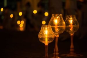 Three candle-lit glass lanterns photography with warmer light in a row with a blurry background.