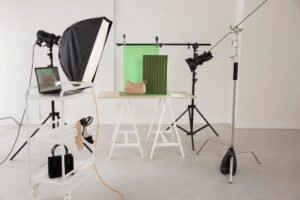 Photography studio setup with lights, laptop, and handbags on display.