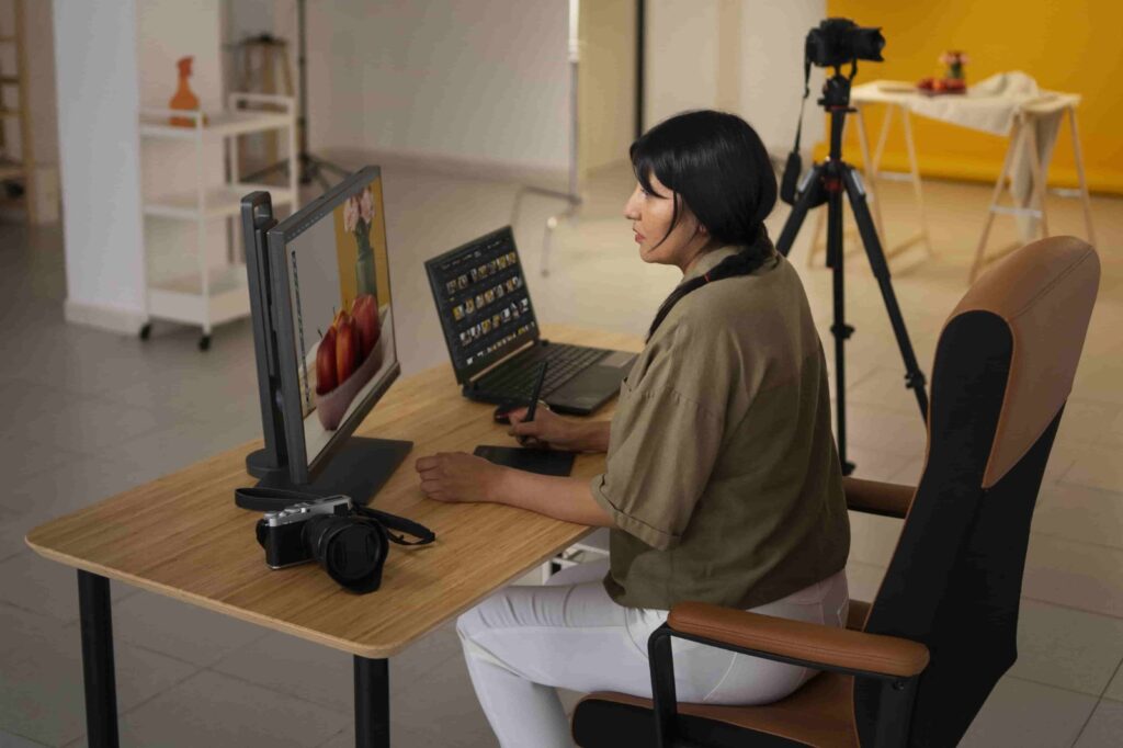 Woman working on laptop with camera nearby, highlighting common photo editing mistakes to avoid in photography workflow.