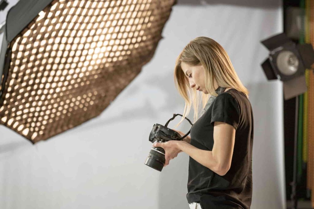 Photographer working in studio with professional camera and softbox lighting, capturing images to monetize photography skills.