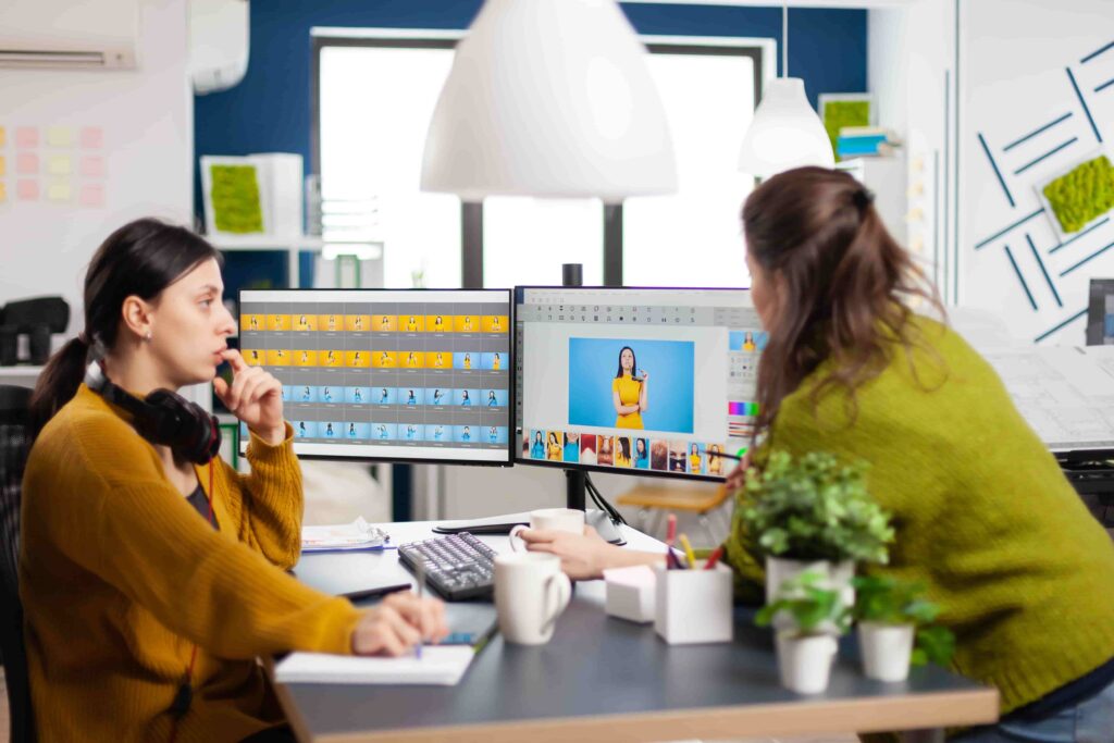 Creative team collaborating on short Instagram video content with dual monitors displaying graphic designs in a bright, modern workspace.