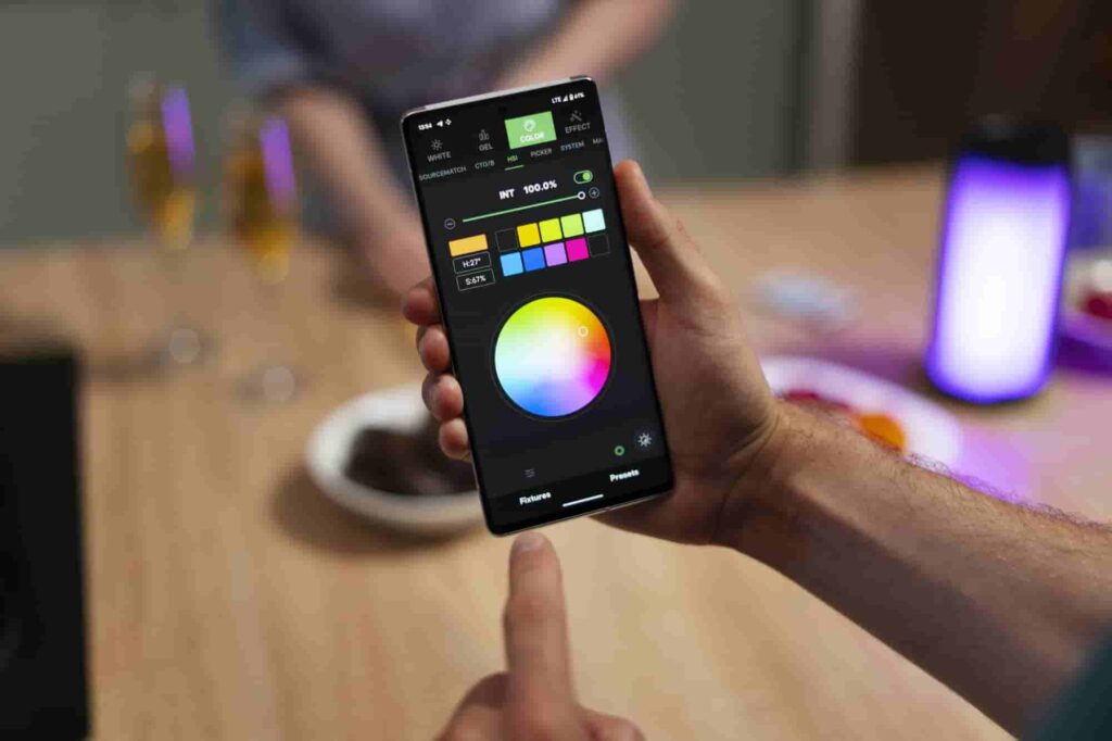 Using a smartphone color picker app to adjust lighting and tones for mobile photo editing, with snacks and drinks in the background.