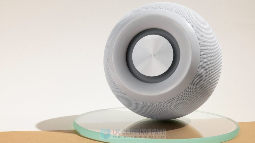 Modern wireless speaker with textured surface on glass platform, featuring minimalist background and refined lighting — highlighting current product photo editing trends.