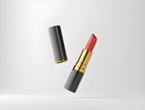 A vibrant red lipstick is partially ejected from a sleek black and gold tube against a minimalist white background.