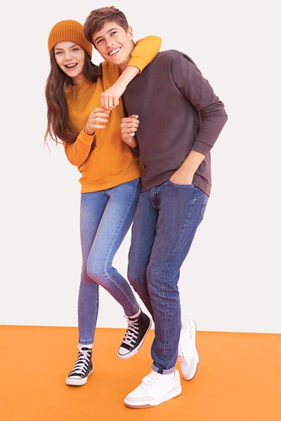 A young couple smiling and posing for a photo on an orange floor.